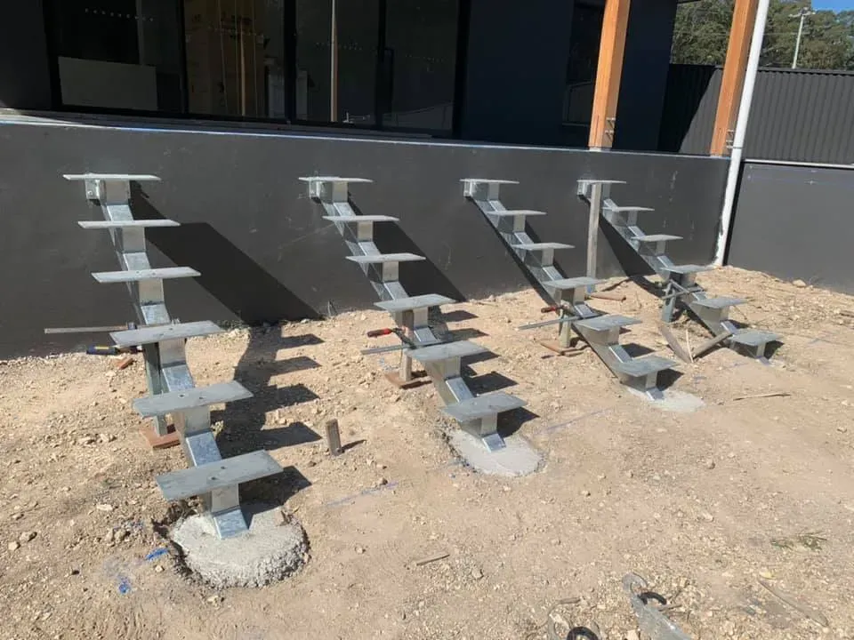 A row of metal stairs are sitting in the dirt in front of a building.