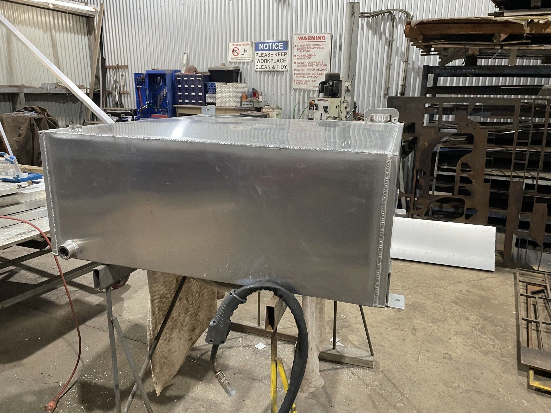 A large aluminum tank is sitting on a table in a factory.