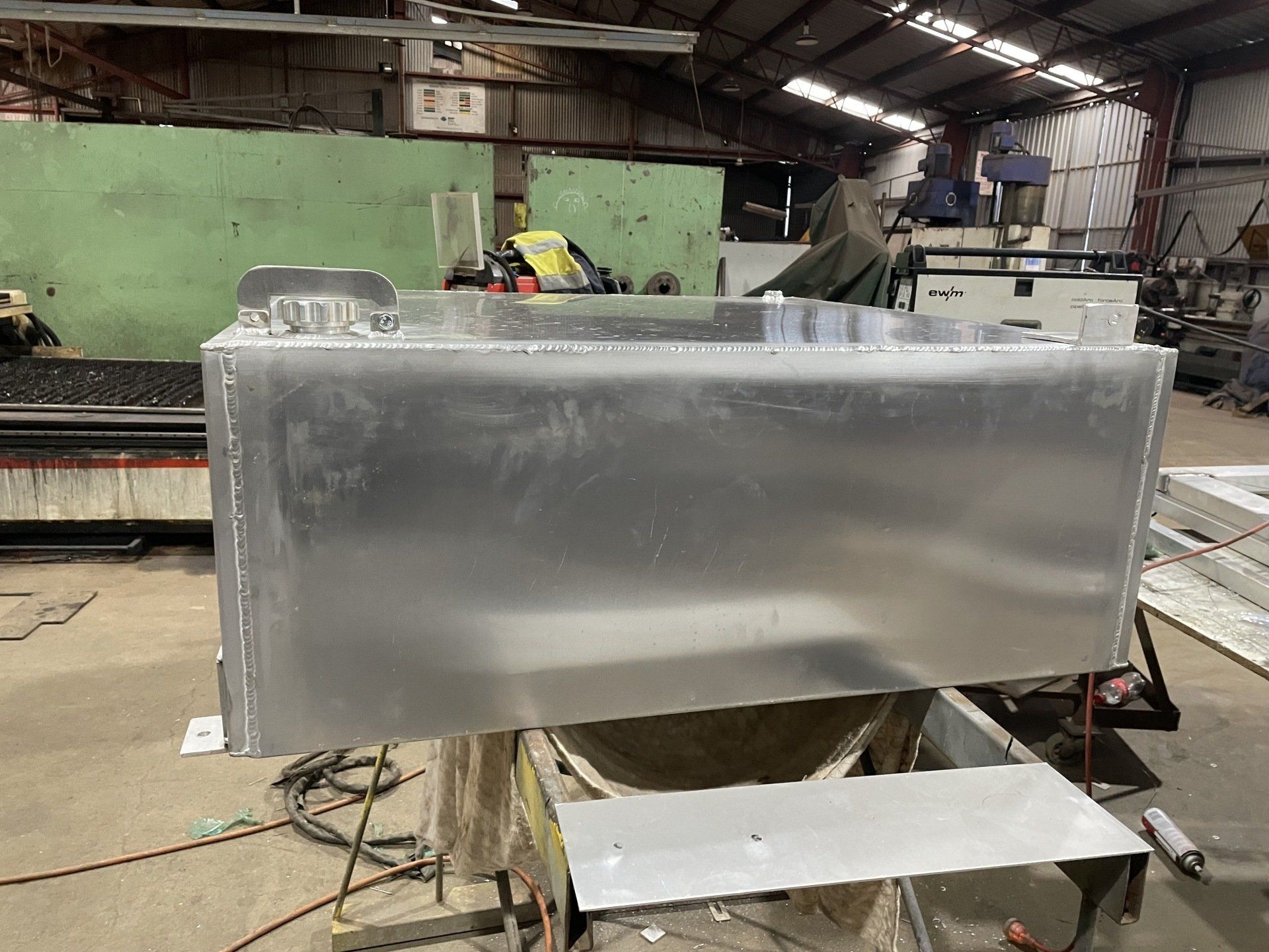 A large aluminum tank is sitting on top of a table in a factory.