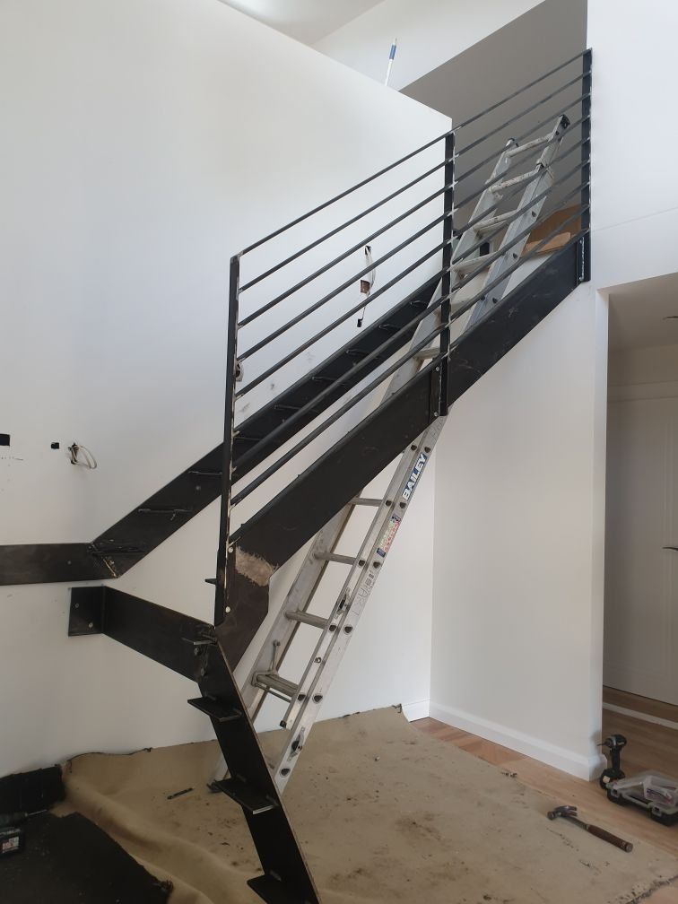 A staircase with a metal railing and a ladder