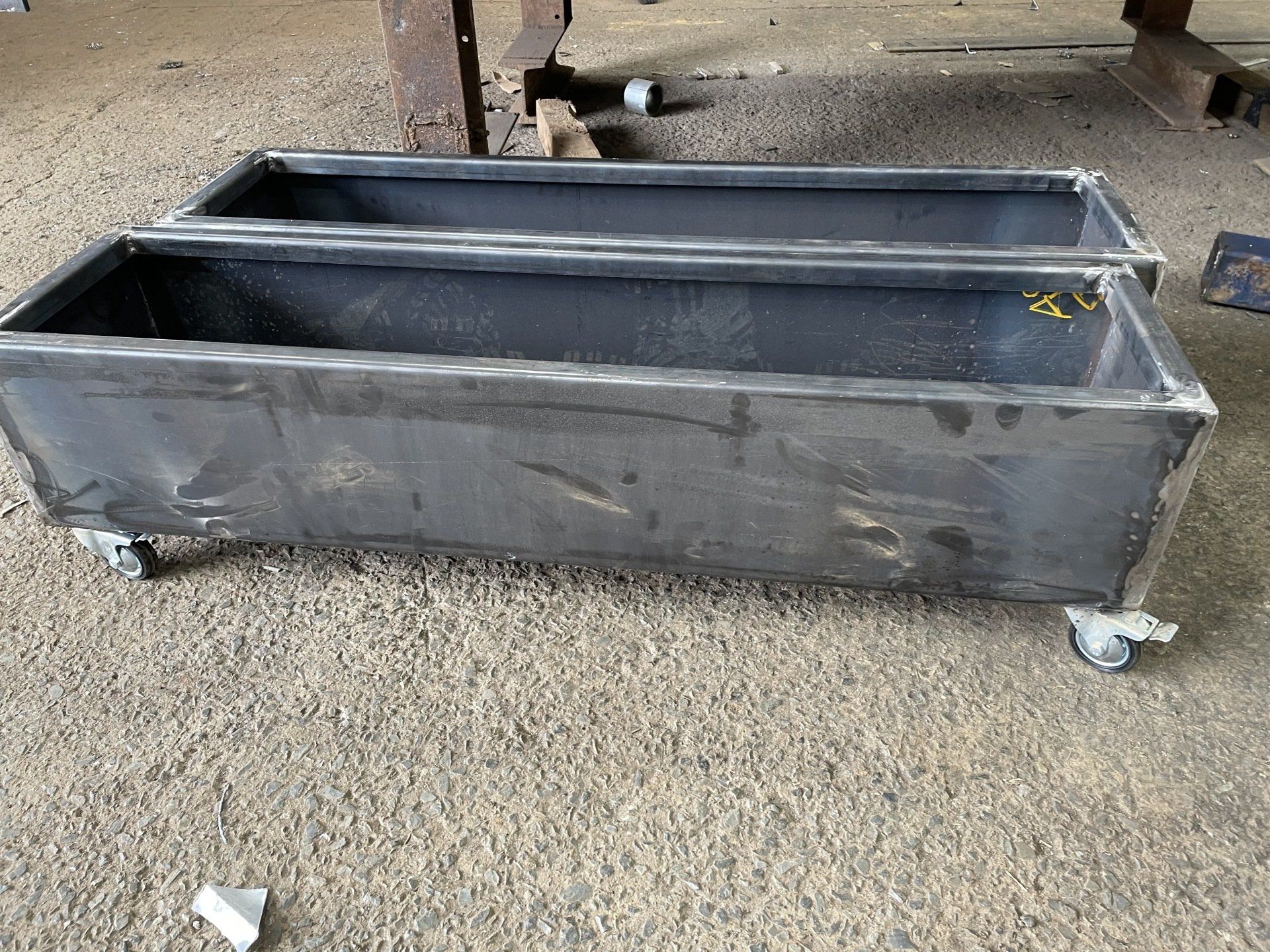 Two metal boxes with wheels are sitting on the ground.