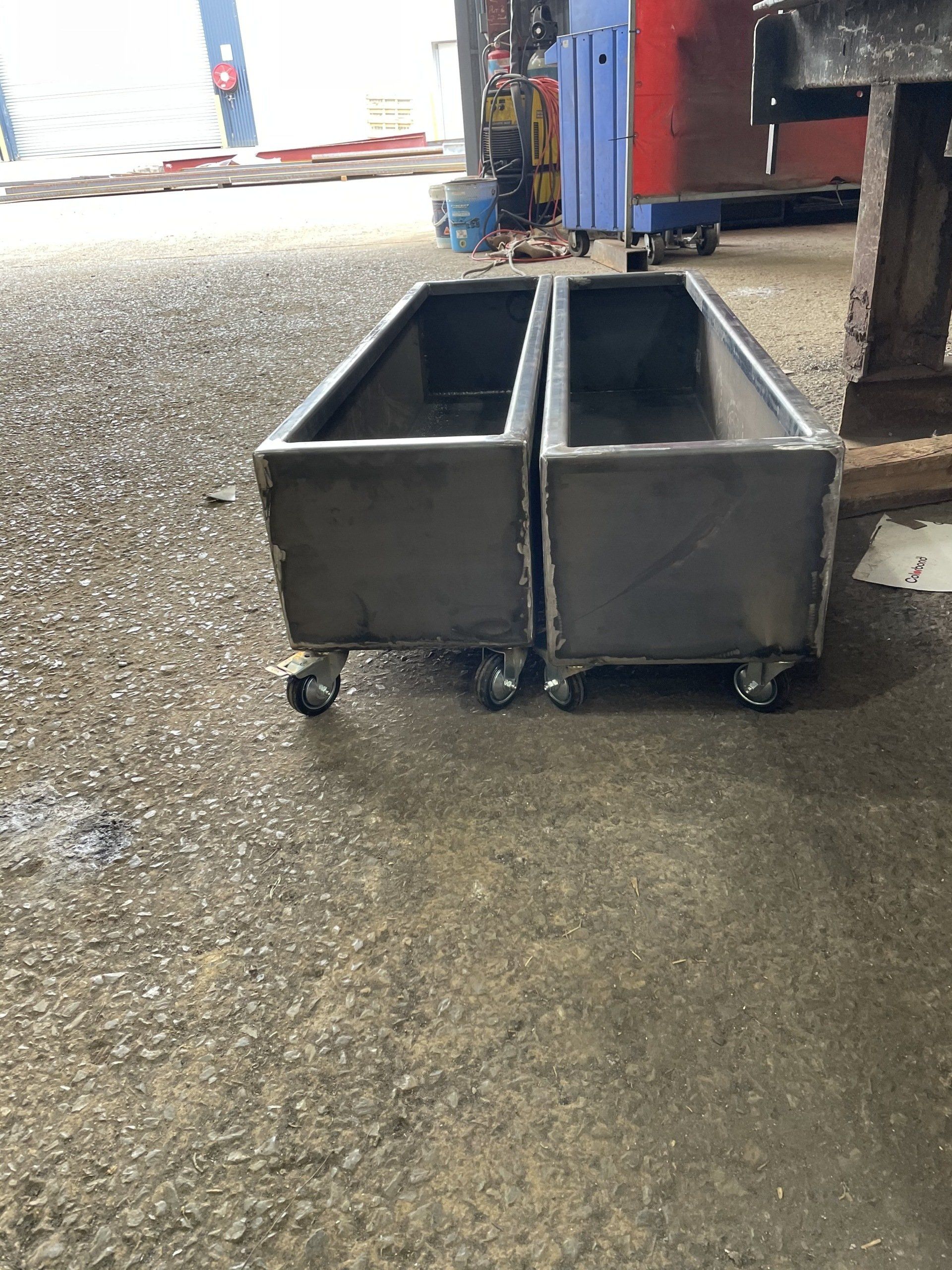 Two metal planters with wheels are sitting on the ground