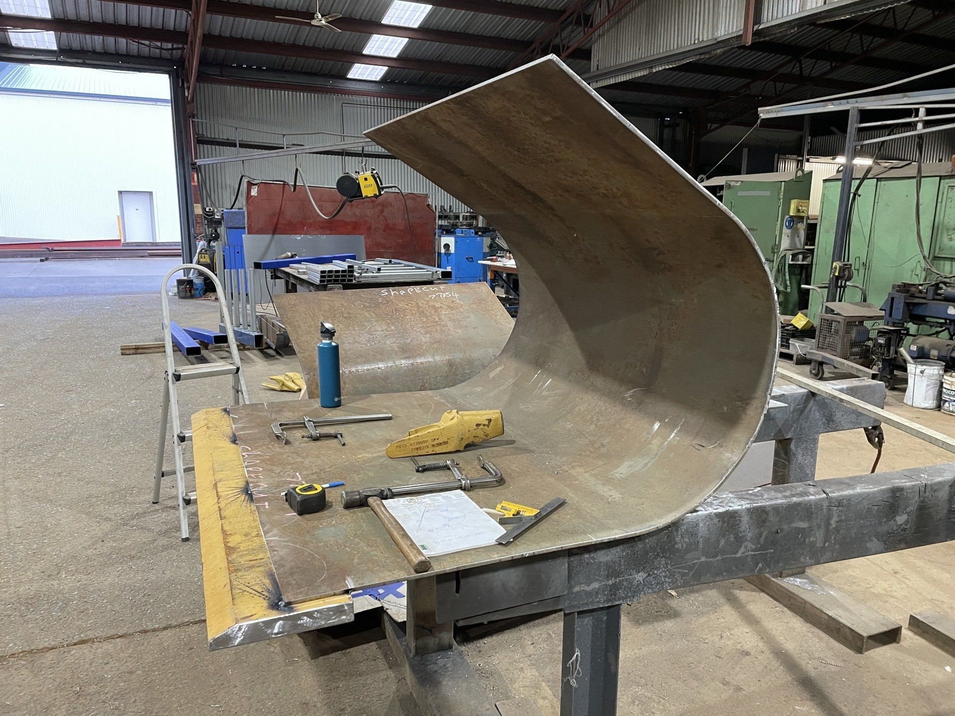 A large piece of metal is sitting on top of a table in a factory.