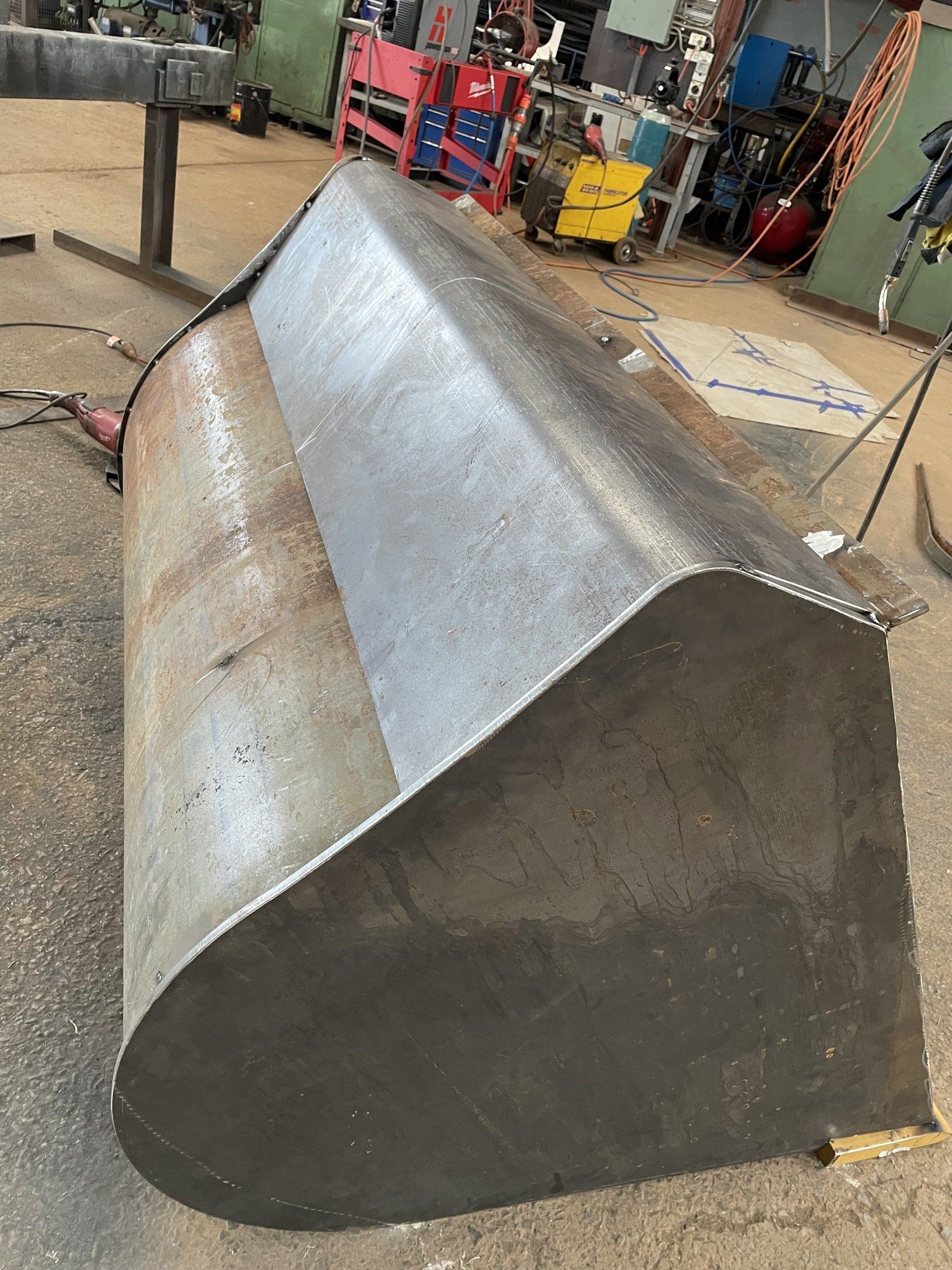 A large metal bucket is sitting on the ground in a factory.
