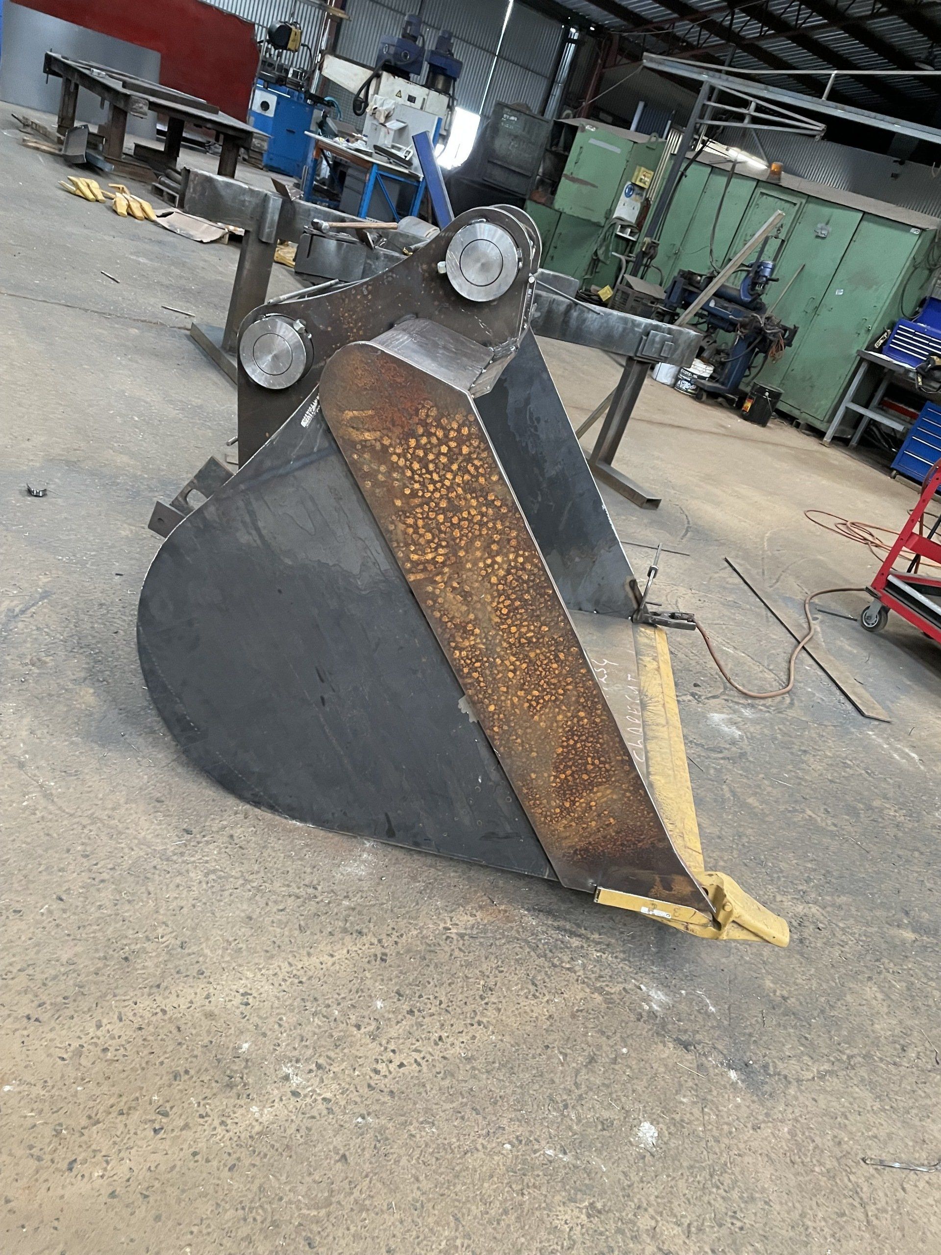 A rusty metal bucket is sitting on the ground in a factory.