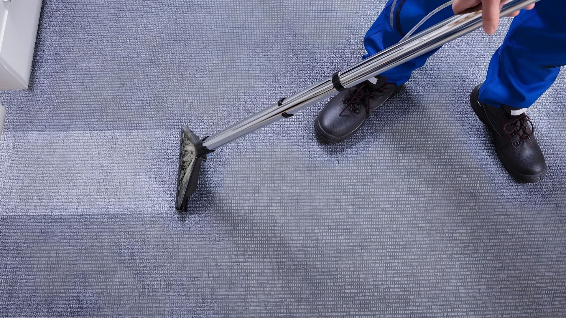 Person scrubbing a large patterned rug on a worktable with soap and water