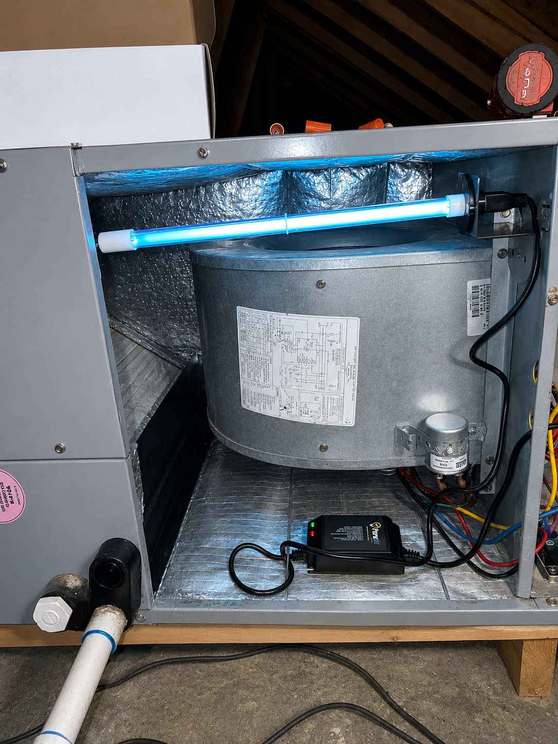 Open appliance cabinet with a large metal cylinder, wires, and tubing inside; flashlight lies on the floor.