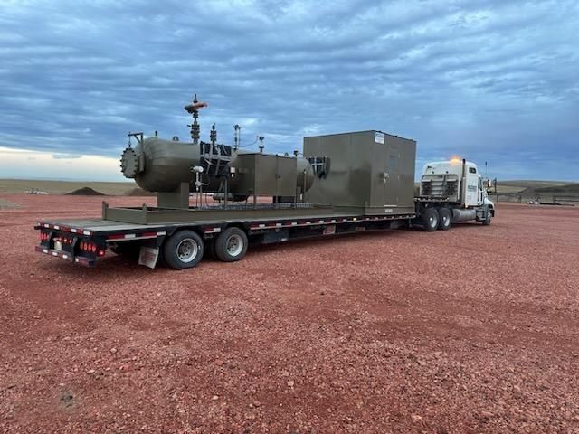 A semi truck is carrying a large piece of equipment on a flatbed trailer.