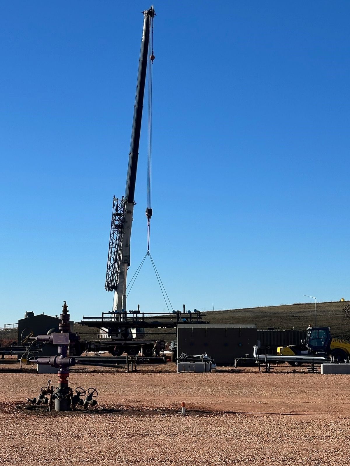 A large crane is lifting equipment in a field