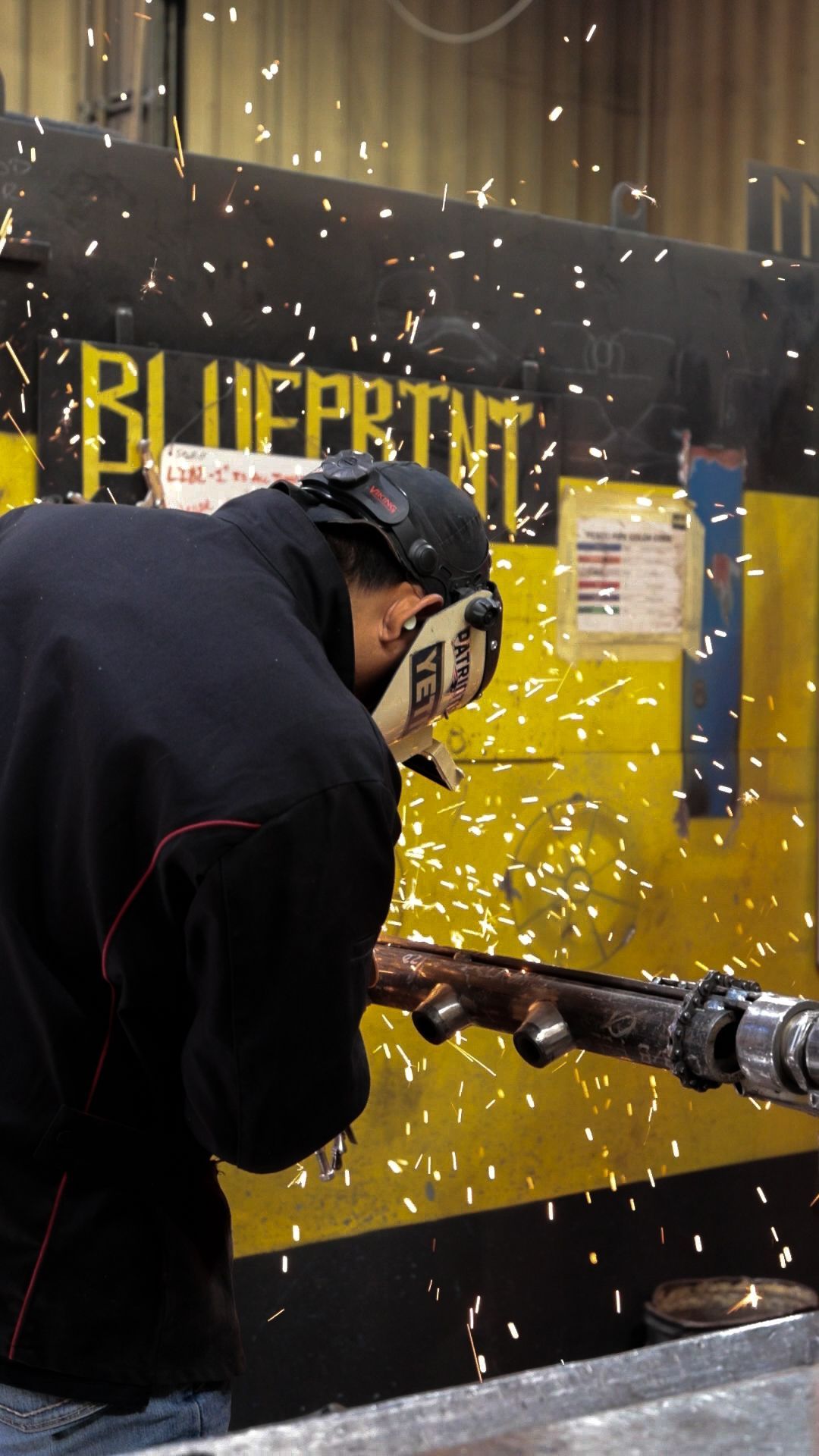 a Pesco employee wearing a welding mask is welding a pipe