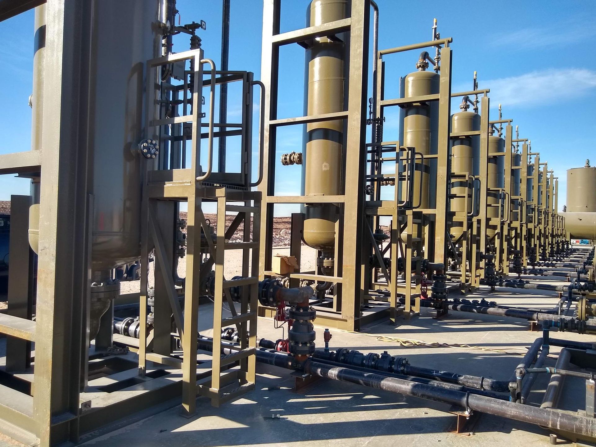 A row of tanks and pipes in a factory on a sunny day