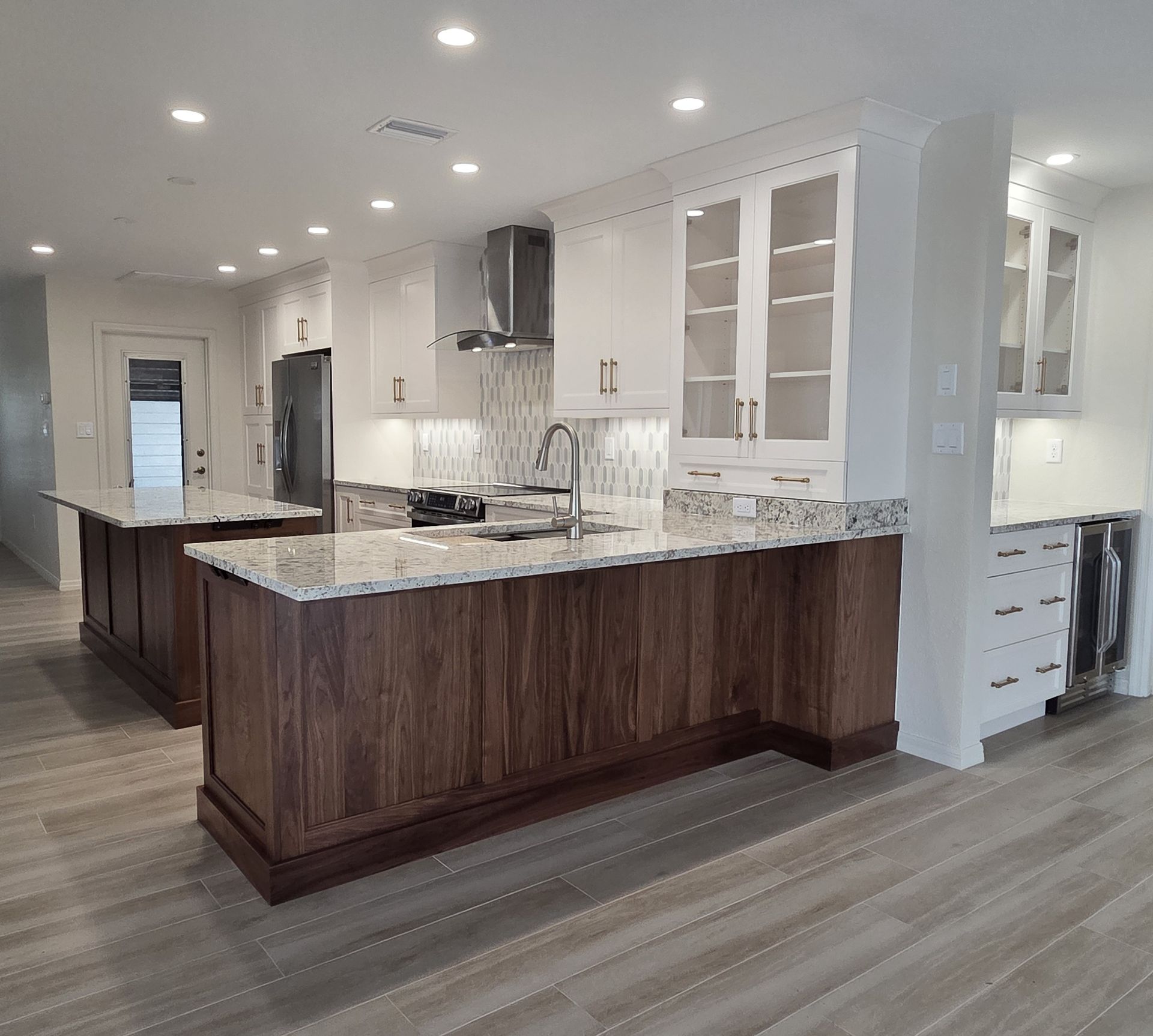Modern kitchen with dark wood island, white cabinets, granite counters, and light wood flooring