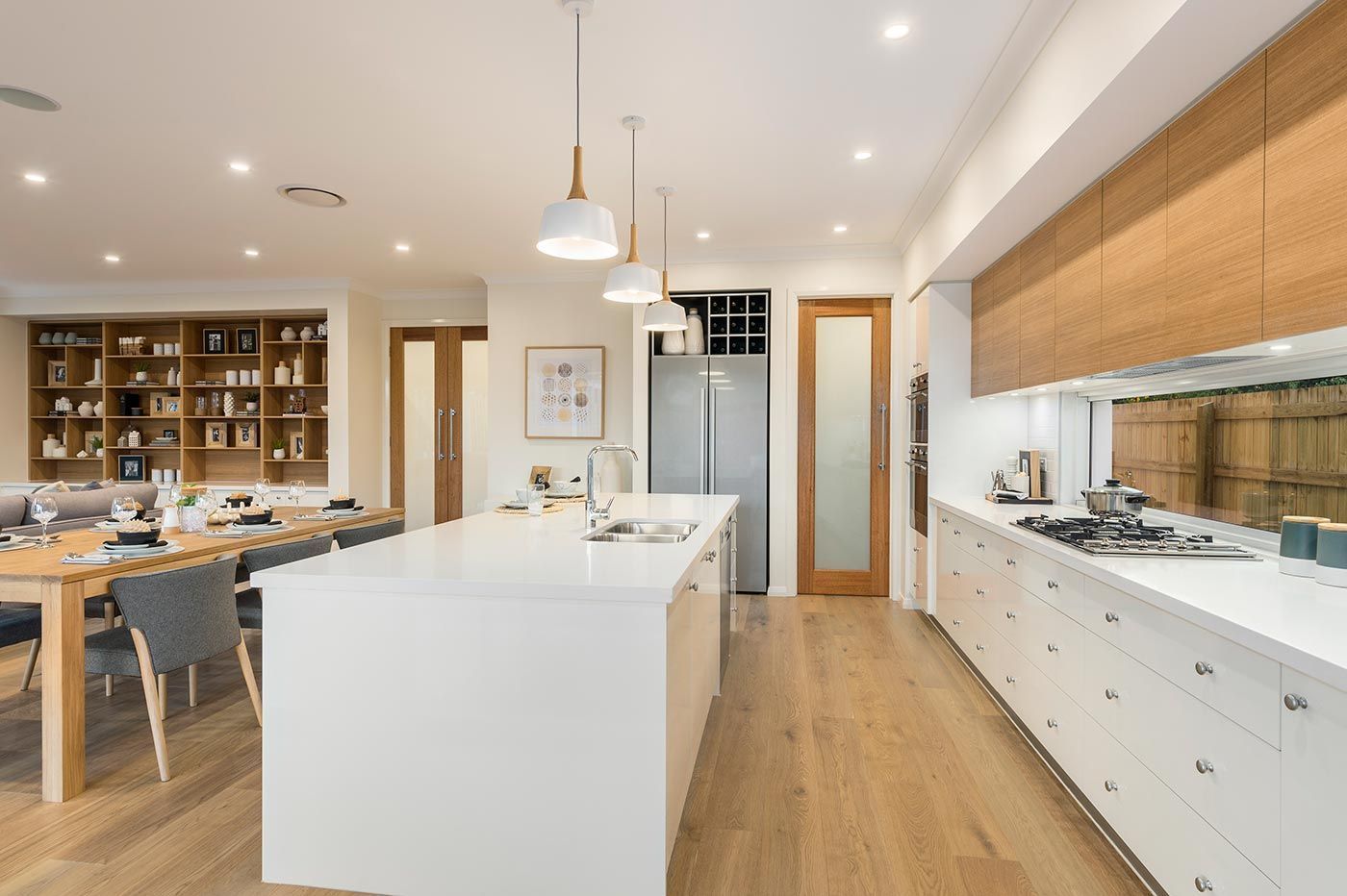Kitchen remodeling in Punta Gorda, FL, bright modern kitchen with white island, wood floors, dining table, and built-in cabinetry