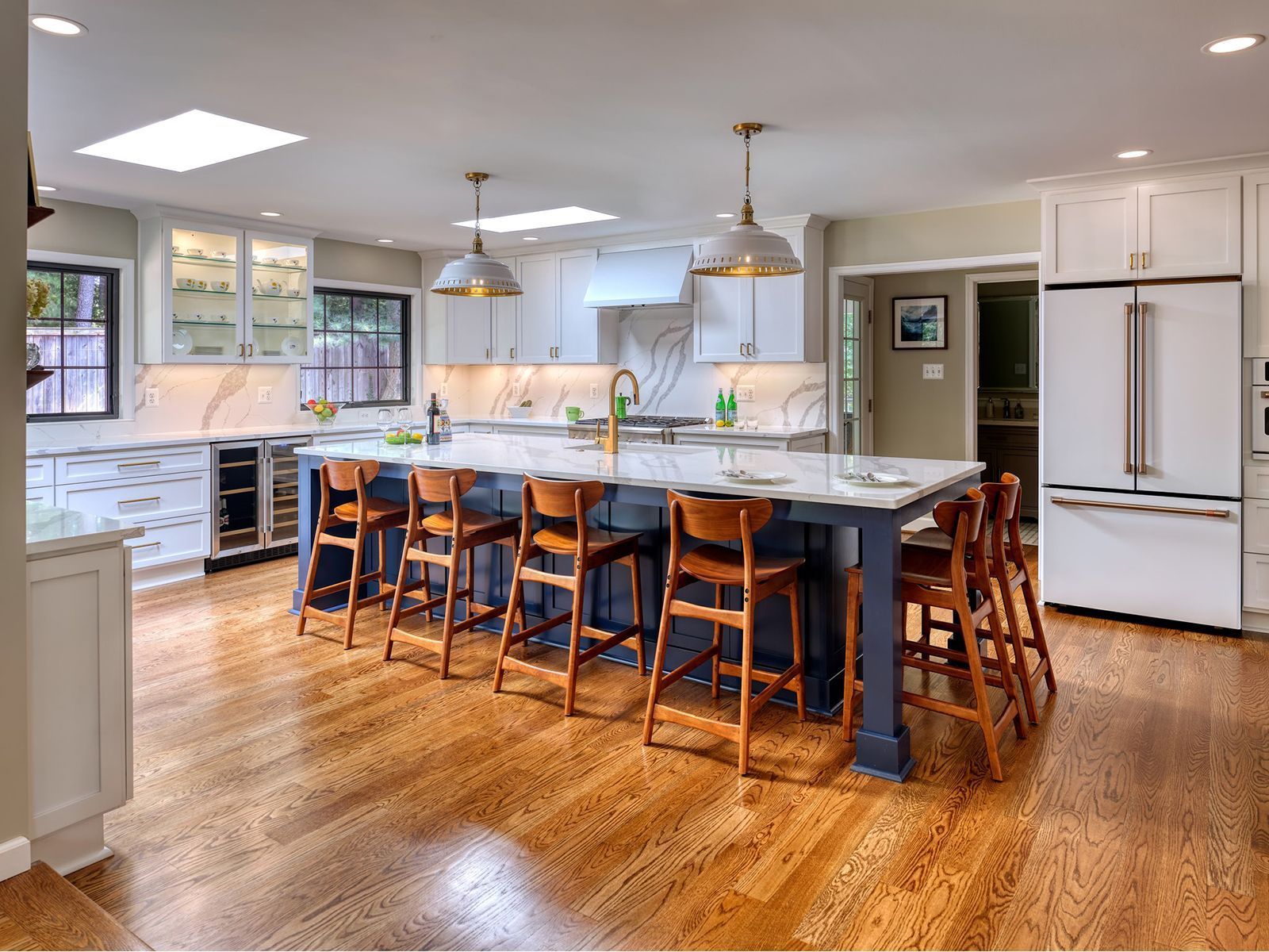 Kitchen remodeling in Punta Gorda, FL, bright modern kitchen with blue island, wooden stools, white cabinets, and hardwood floors