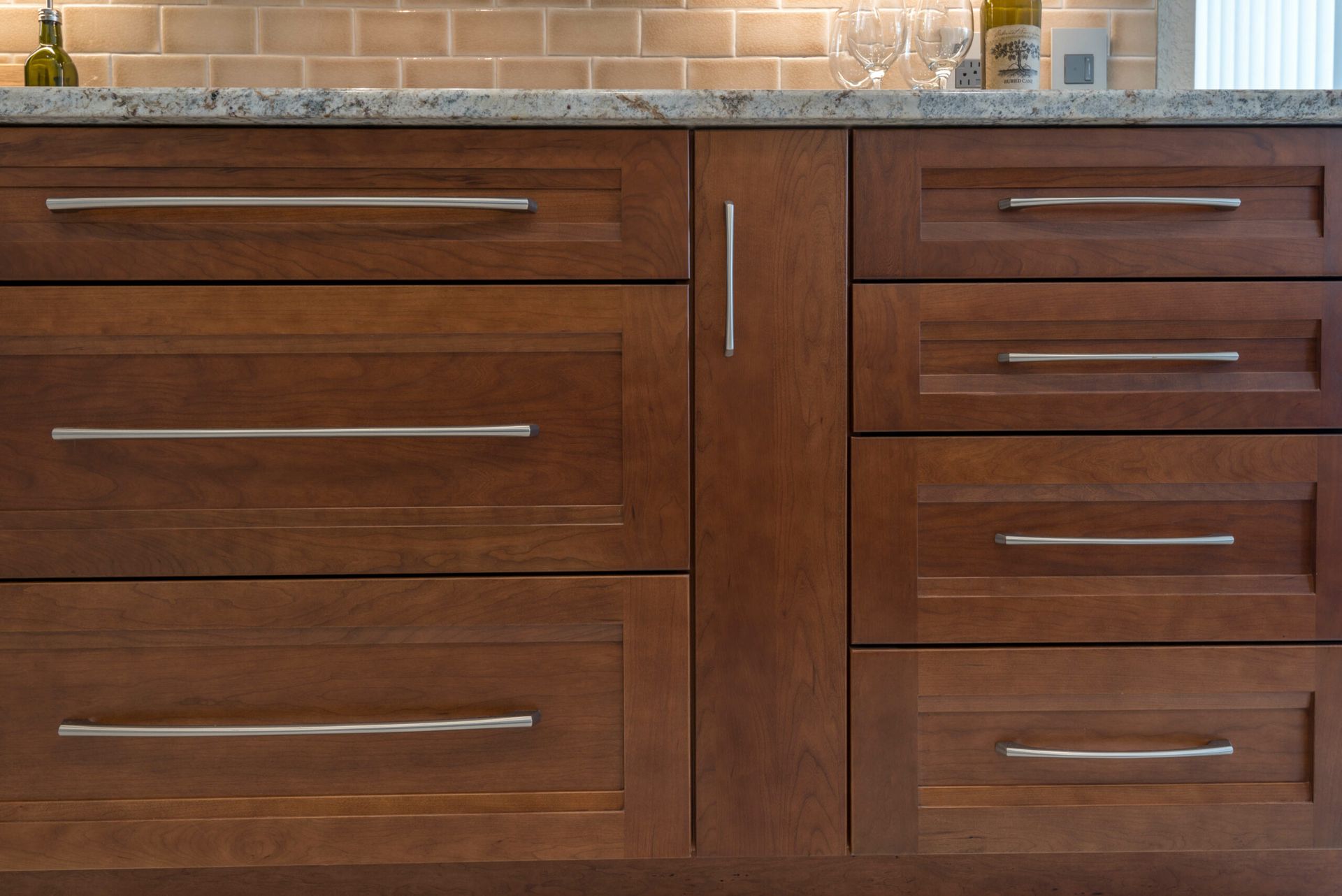 Dark wood kitchen cabinets with brushed metal handles below a tiled backsplash.