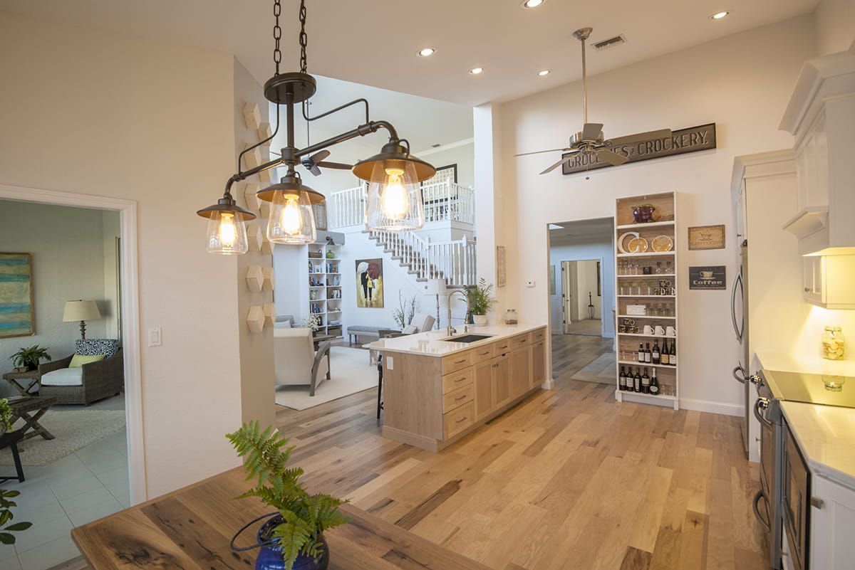 Modern kitchen with wood floors, island, pendant lights, and white cabinets with open shelving