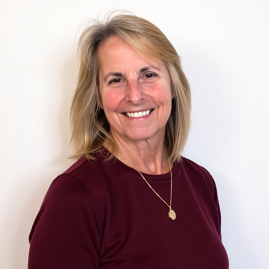 Smiling woman in maroon top and gold necklace against a white background