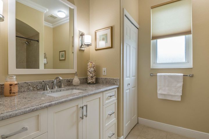 Bright bathroom with granite vanity, large mirror, and window with towel rack.