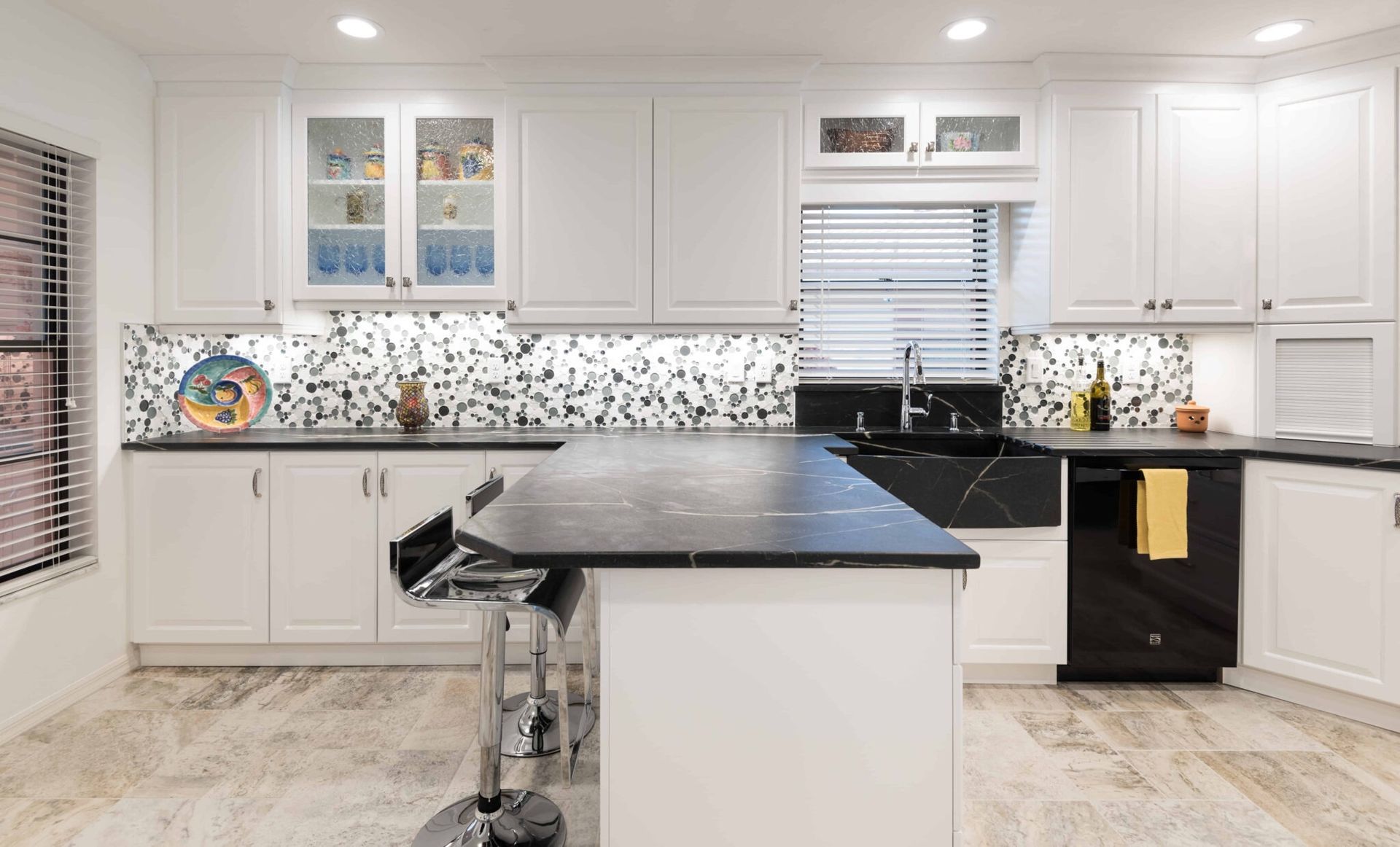 Bright modern kitchen with white cabinets, black island countertop, and stainless appliances
