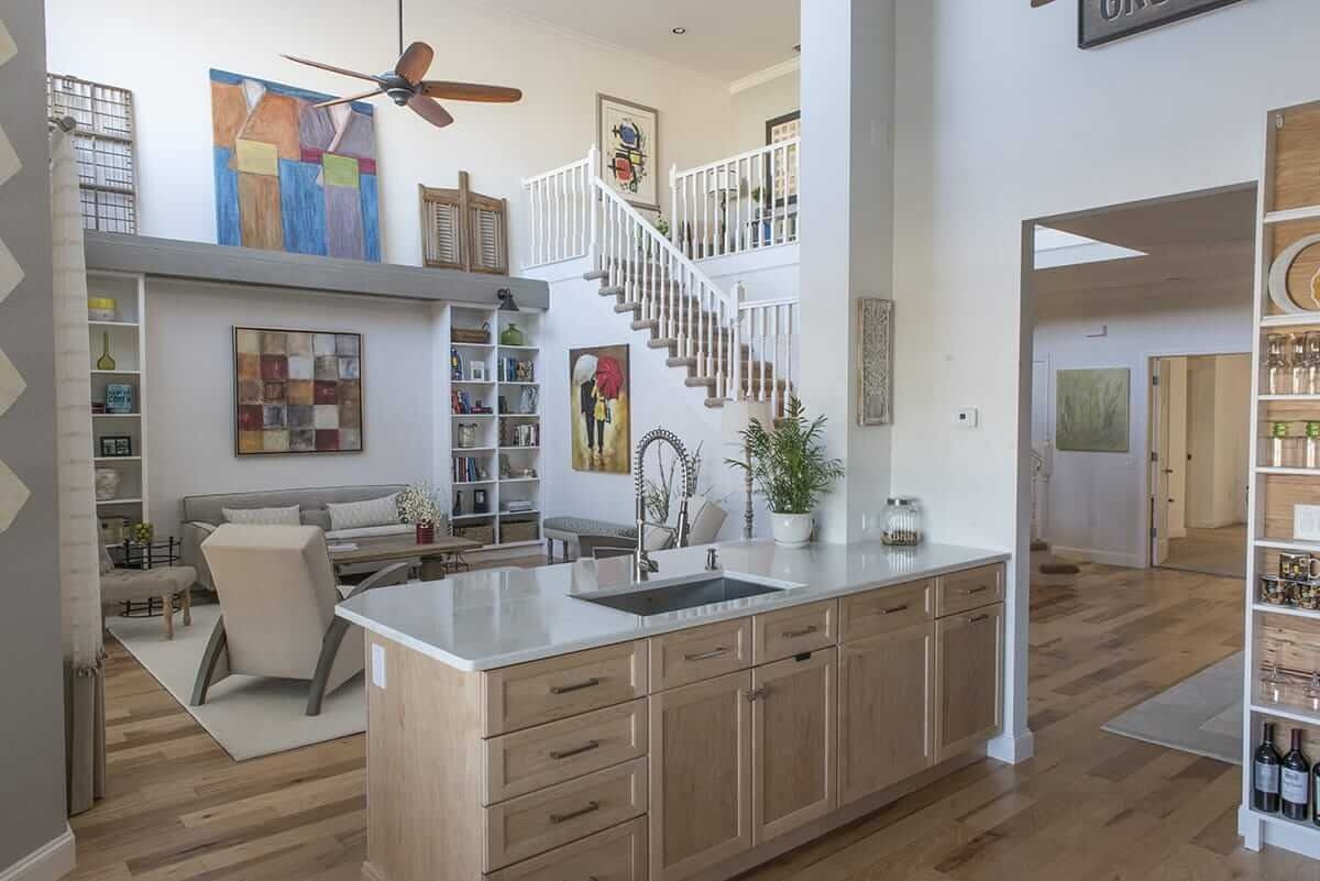 Open-concept kitchen and living room with island, staircase, and bright modern decor