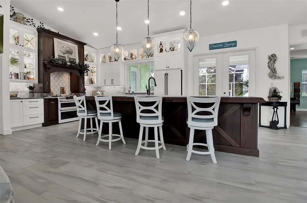 Bright modern kitchen with a large island, bar stools, pendant lights, and white cabinets.
