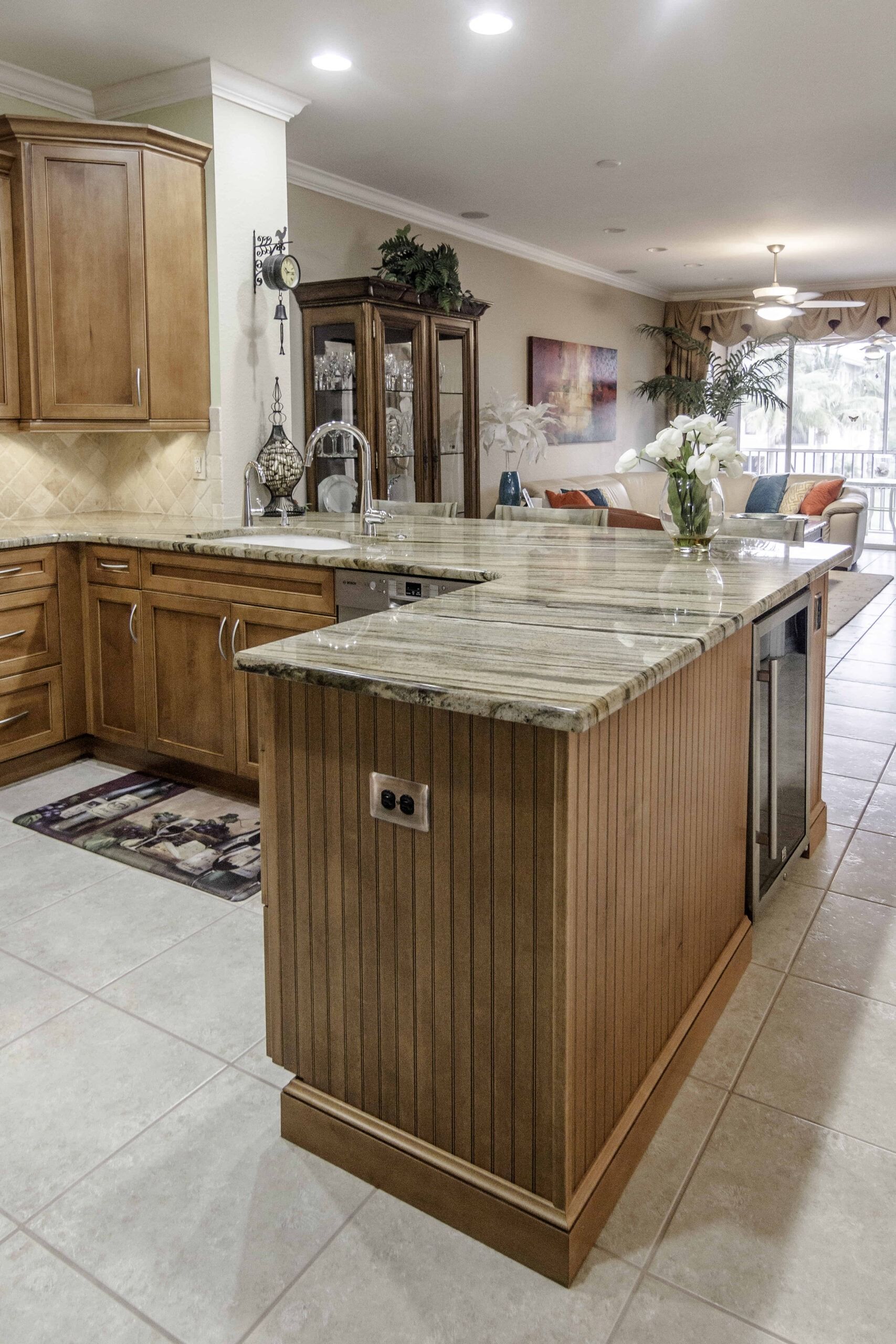 Modern kitchen with wood cabinets, granite island, tiled floor, and glass china cabinet