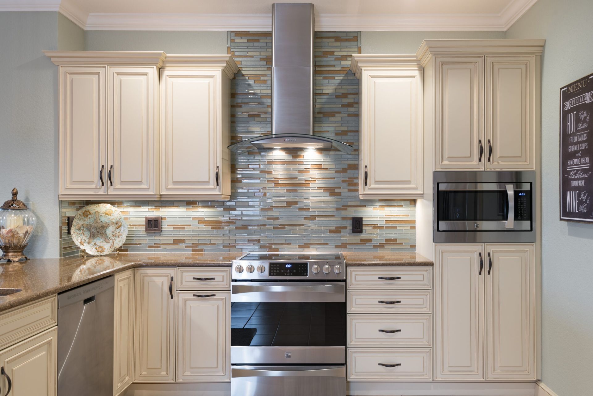 Modern kitchen with cream cabinets, stainless steel appliances, and blue-gray tile backsplash