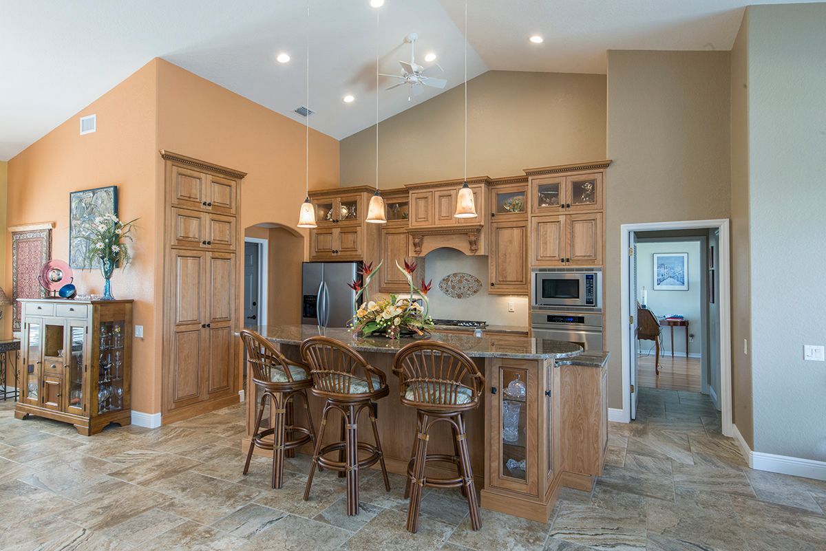 Open-concept kitchen with wood cabinets, granite island, and bar stools in a bright home interior