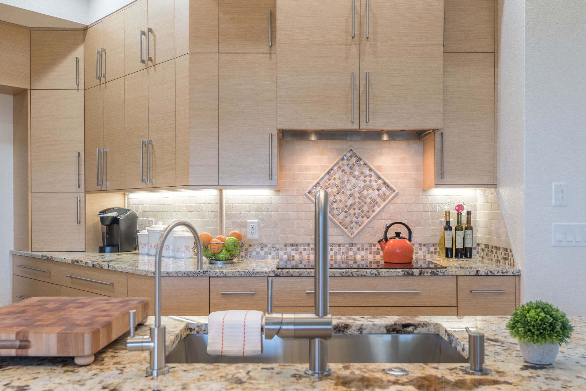 Kitchen remodeling in Punta Gorda, FL, modern kitchen with granite island, stainless sink, wood cabinets, and a tiled backsplash