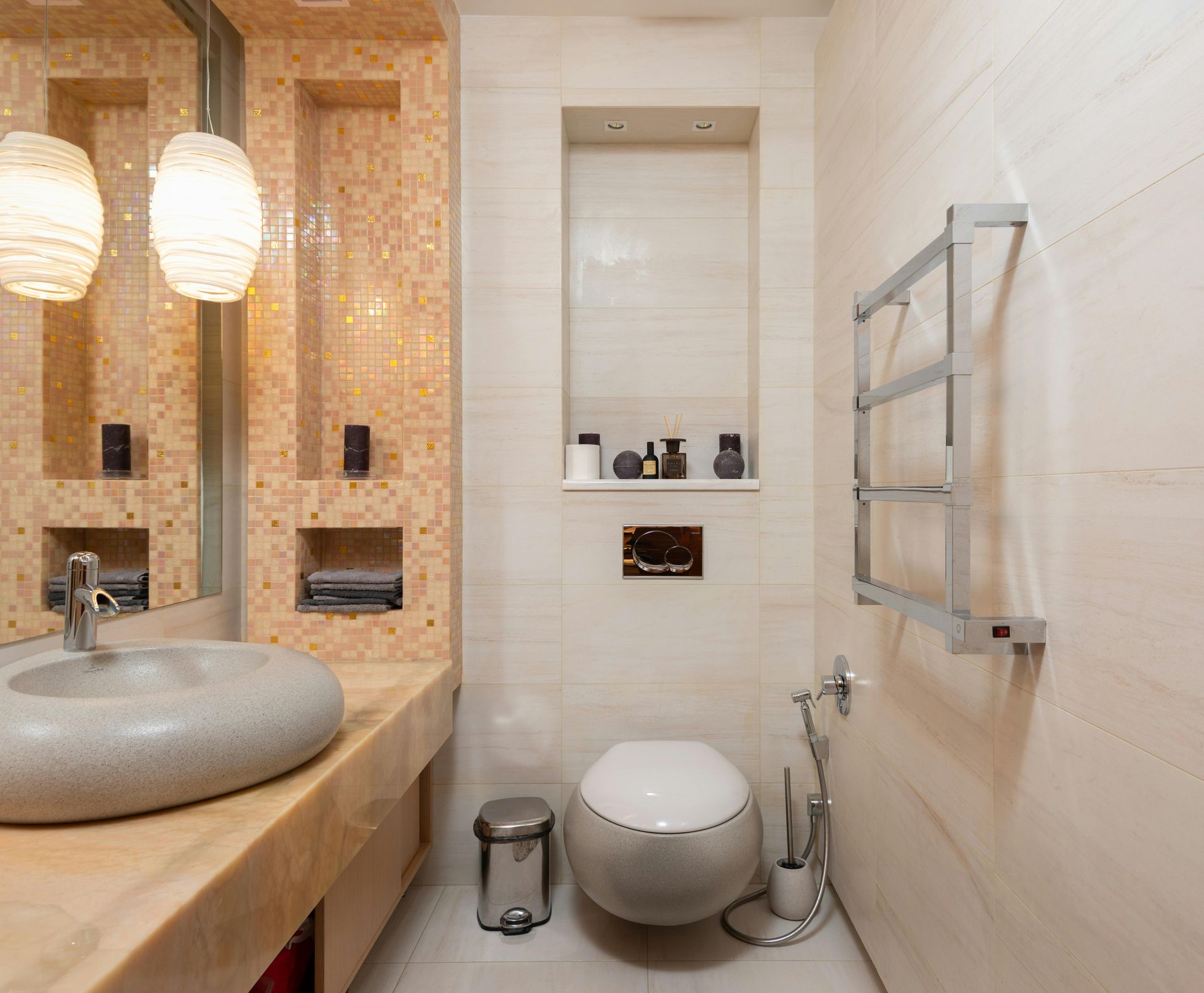 Modern beige bathroom with vessel sink, toilet, wall mirror, and chrome towel rack