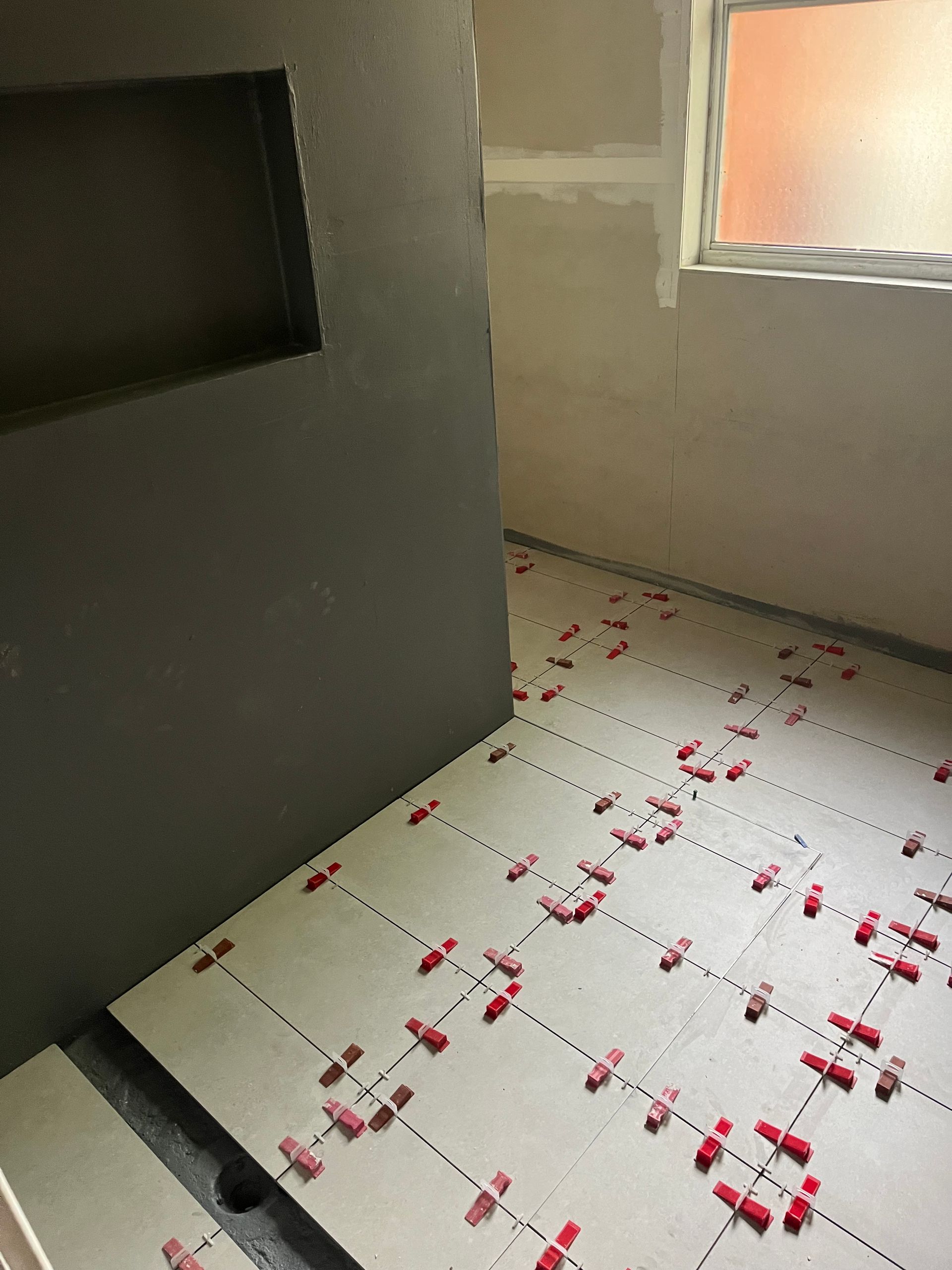 A bathroom floor with a lot of tiles on it and a window — TM Built Construction In Lochinvar, NSW
