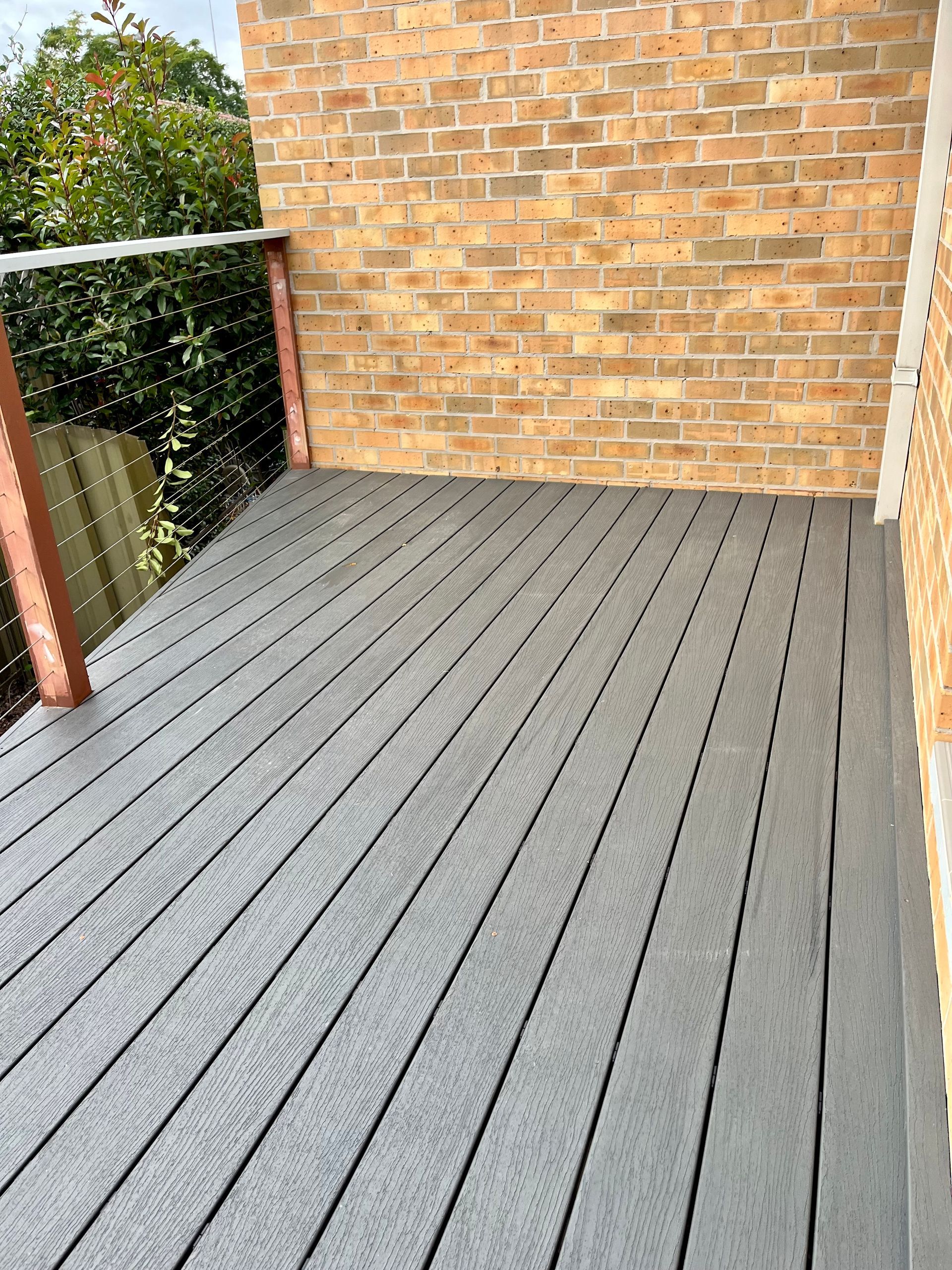 A brick building with a gray deck in front of it — TM Built Construction In Lochinvar, NSW