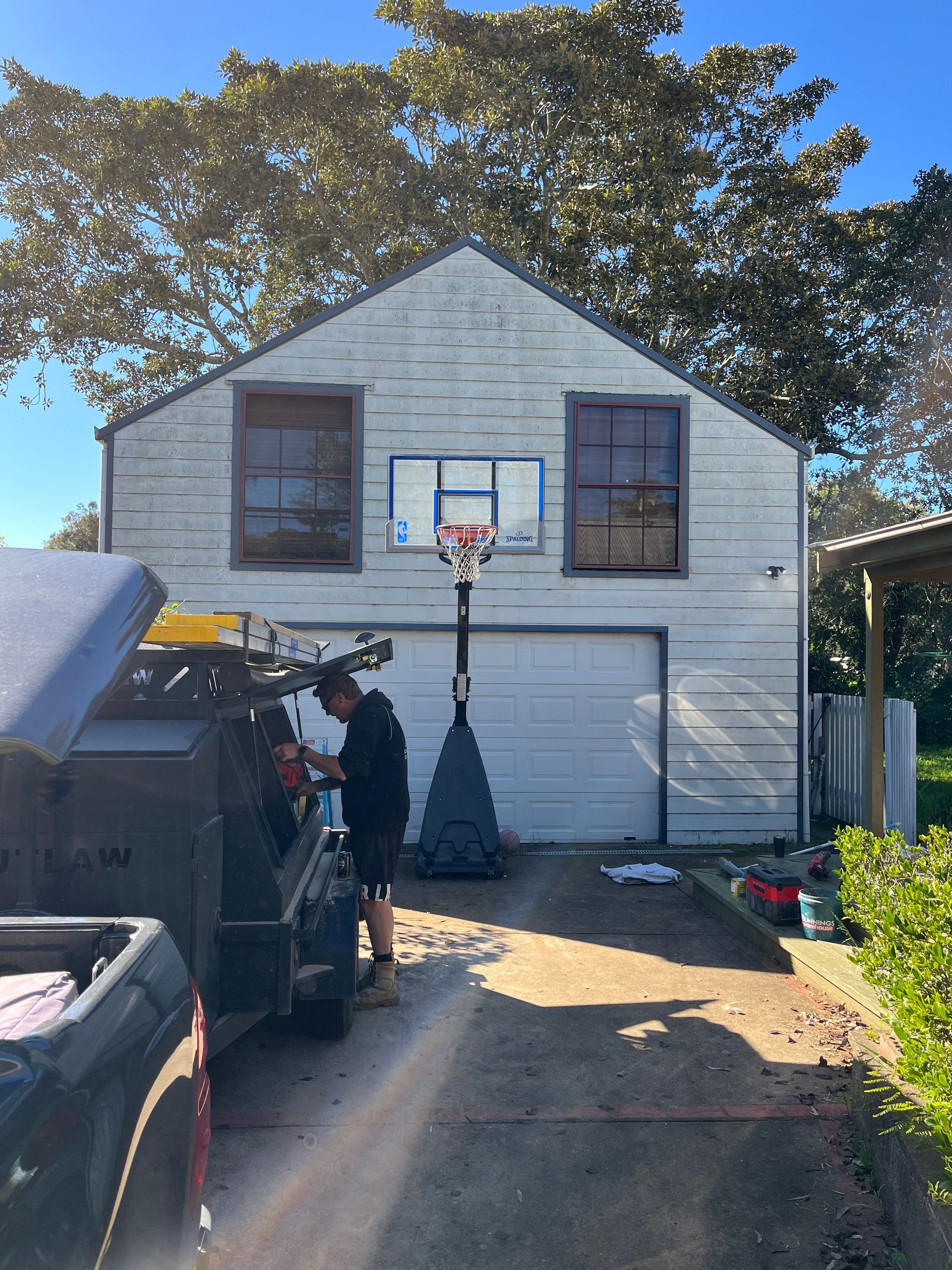 A man is working on a basketball hoop in front of a garage — TM Built Construction In Lochinvar, NSW