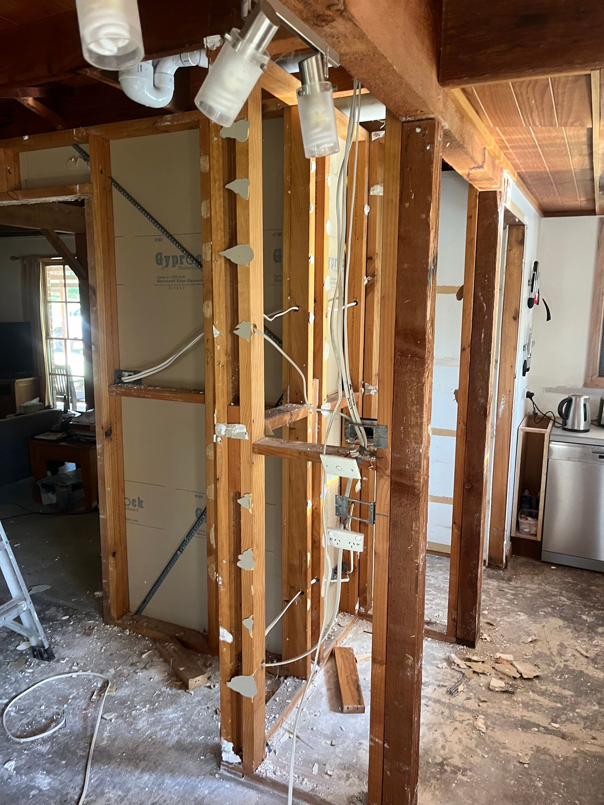 A room that is being remodelled with wooden beams and a ladder — TM Built Construction In Lochinvar, NSW