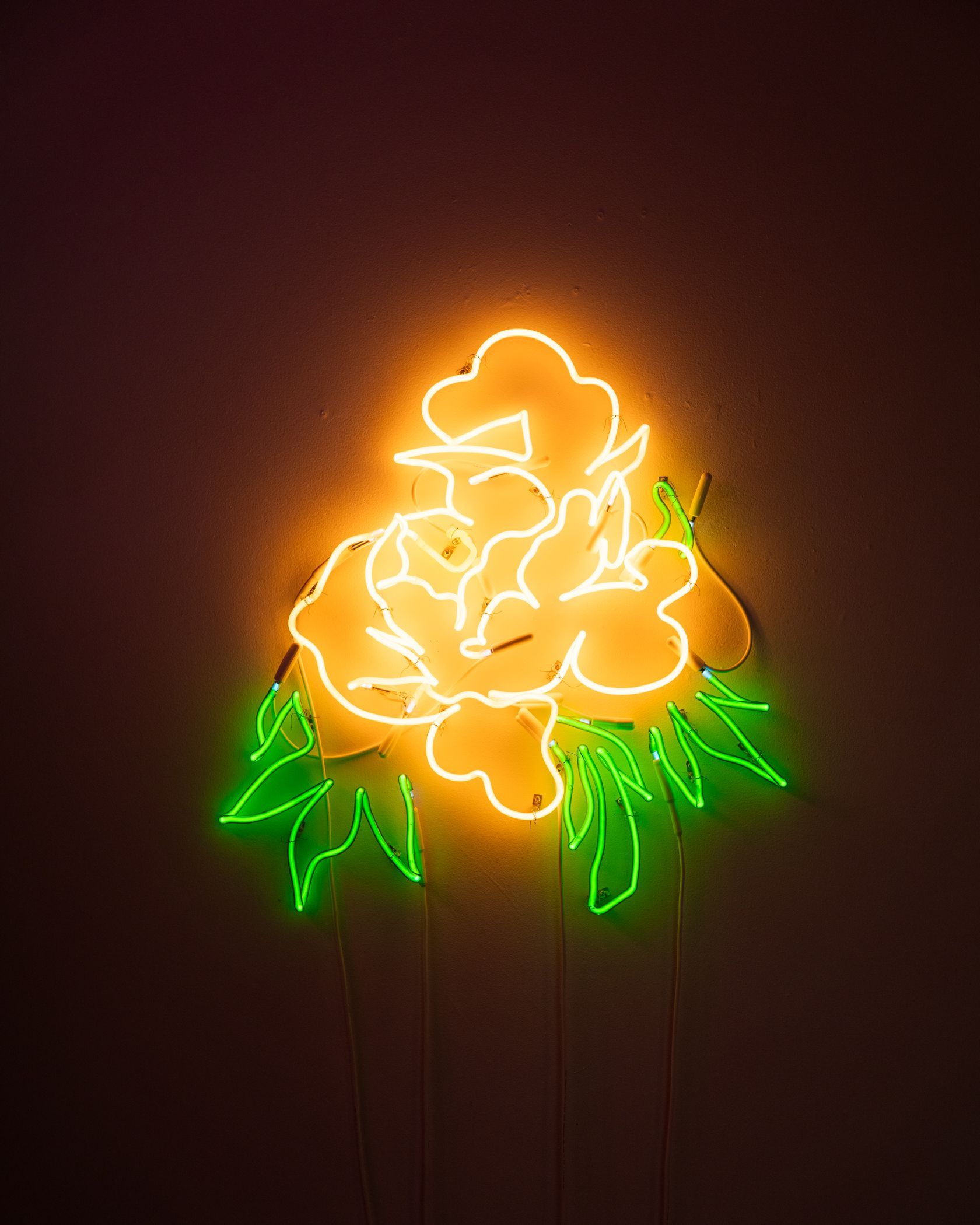 Neon flower sculpture, yellow petals, green leaves, dark background; art by Yale Wolf.