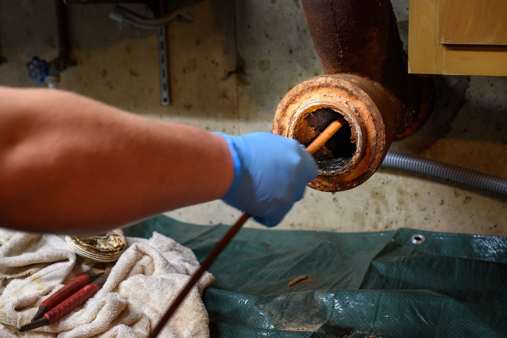Plumber feeding a camera scope into a rusty sewer pipe