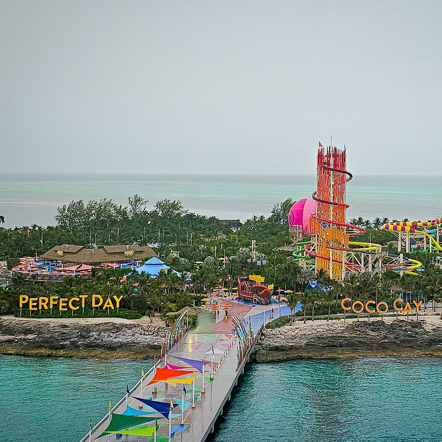 A pier leads to Perfect Day CocoCay, a water park on an island with water slides and colorful structures.