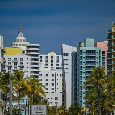 Colorful Art Deco buildings and palm trees against a blue sky in Miami.