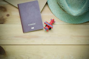 Passport, toy airplane, and hat arranged on a wood surface. Travel concept.