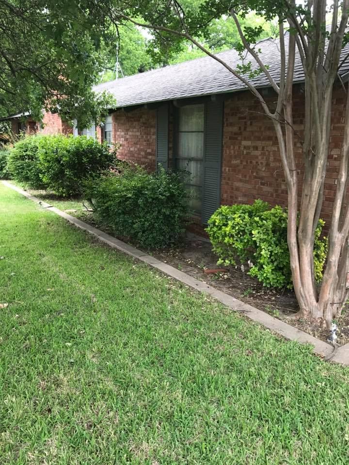 A brick house with a lush green lawn in front of it.