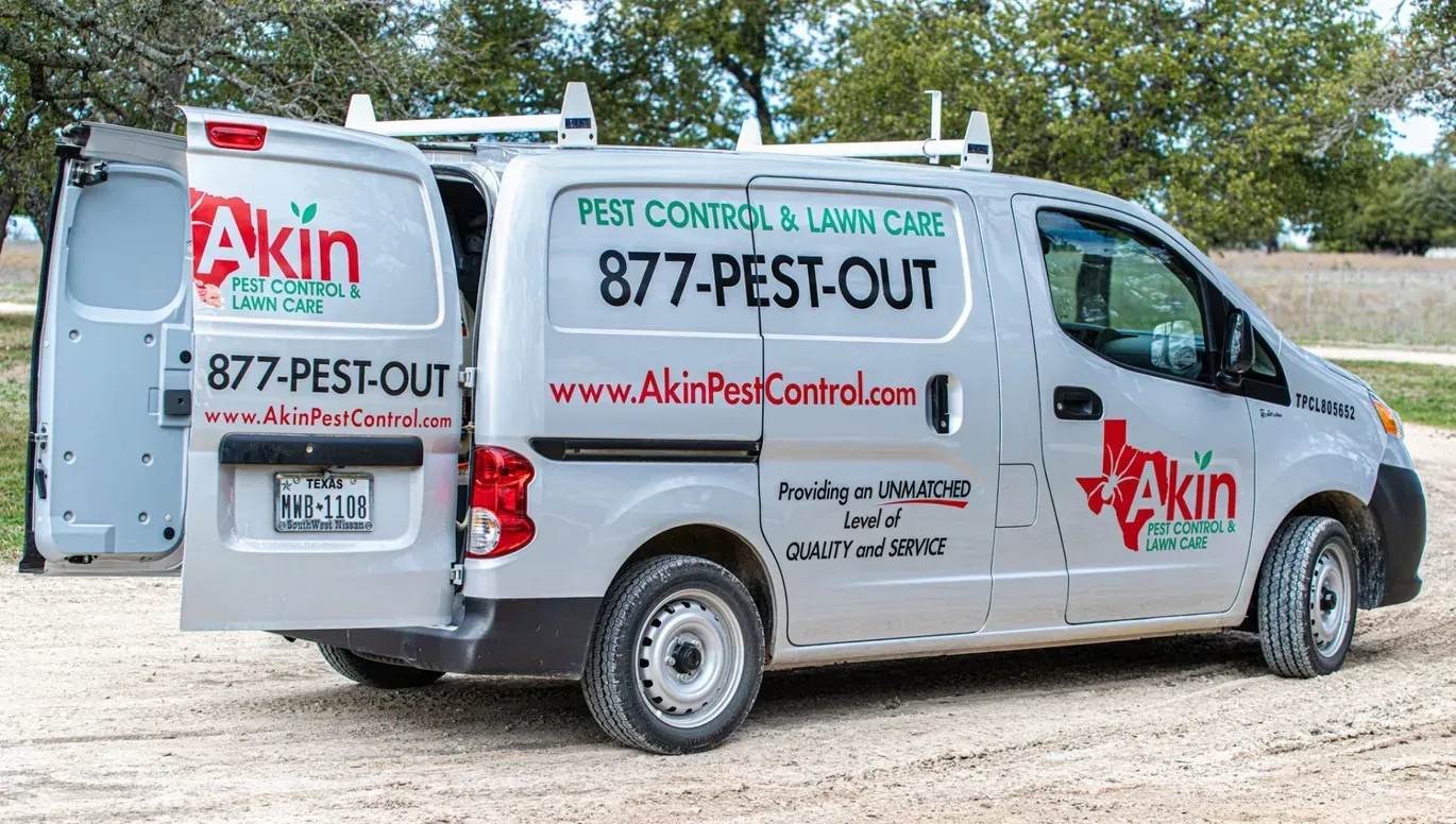 A white van with the door open is parked on a dirt road.