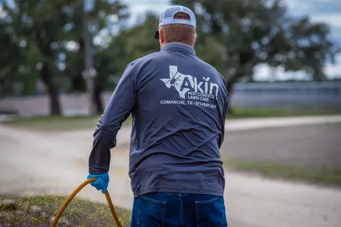 A man is walking down a dirt road holding a hose.