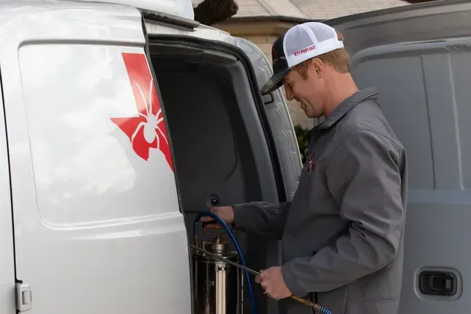 A man is spraying something from the back of a van.