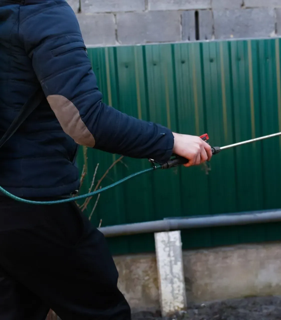 A person is holding a rope in front of a green fence