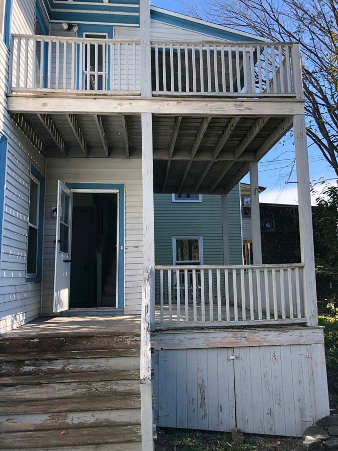 A blue and white house with a porch and stairs