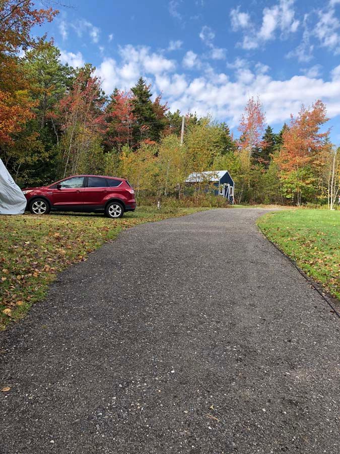 A red car is parked on the side of a road next to a tent.