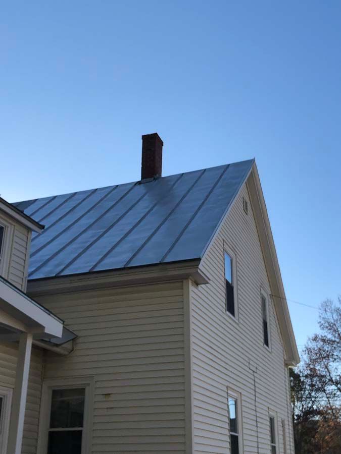 A white house with a metal roof and a chimney