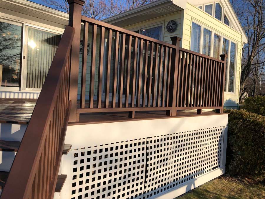 A wooden deck with stairs leading up to it is in front of a house.