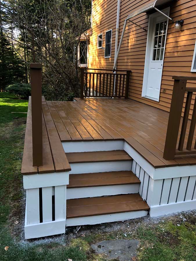 A wooden deck with stairs leading up to it is in front of a house.