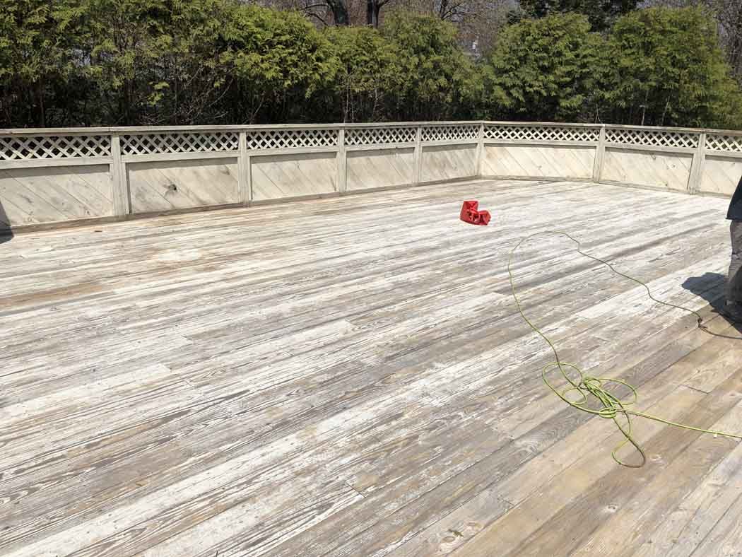 A person is standing on a wooden deck with boxing gloves on it.